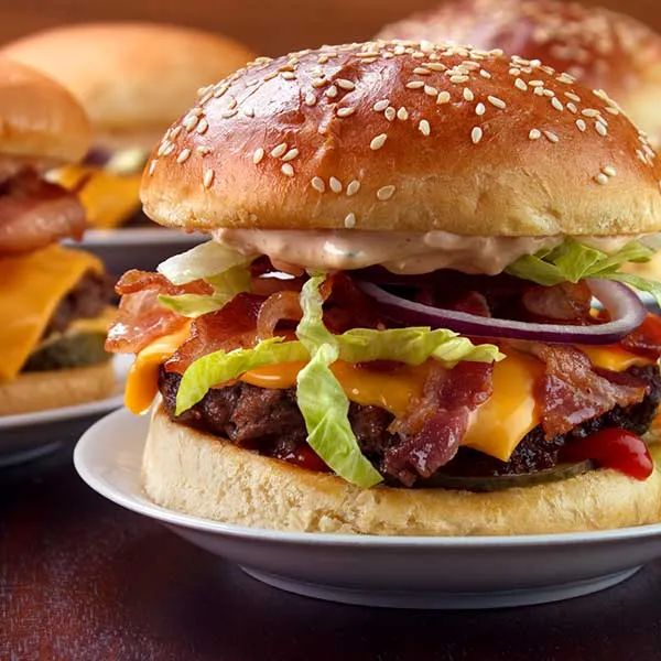 Burger with bacon, cheese, lettuce, and onions