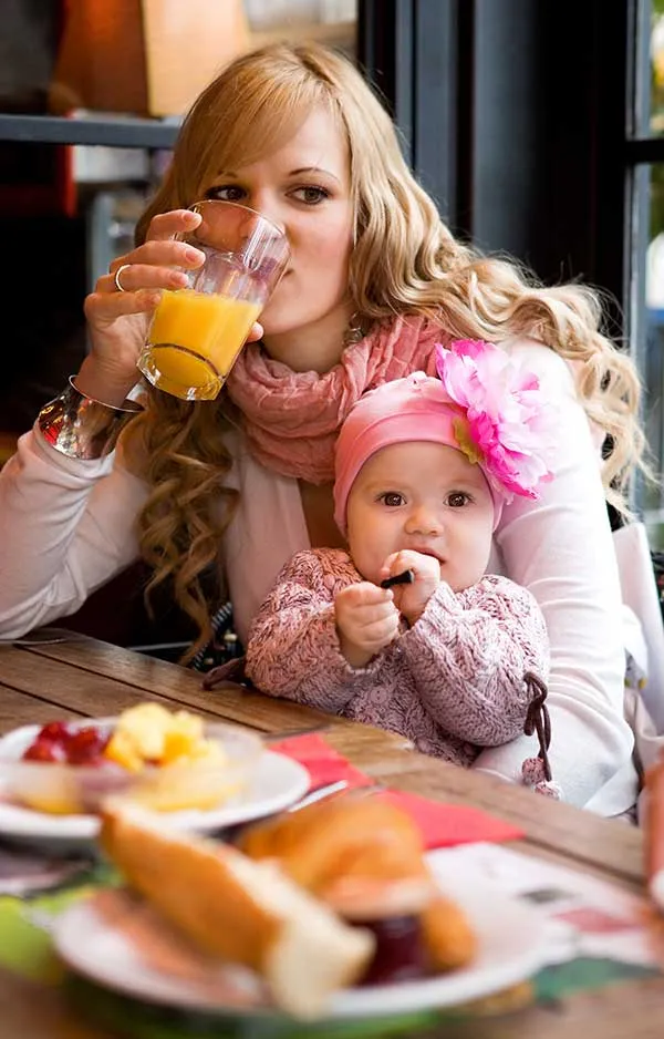 Chatham Breakfast Restaurants, Mother at a table drinking orange juice while holding her child